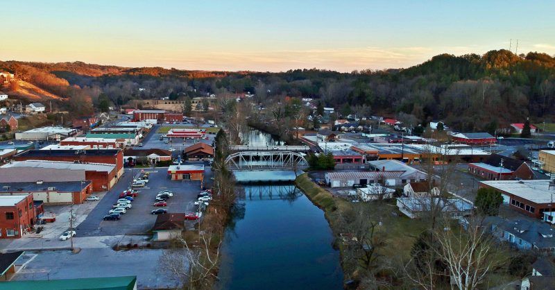 Aerial view of a small town with a river running through it; golden hour light.