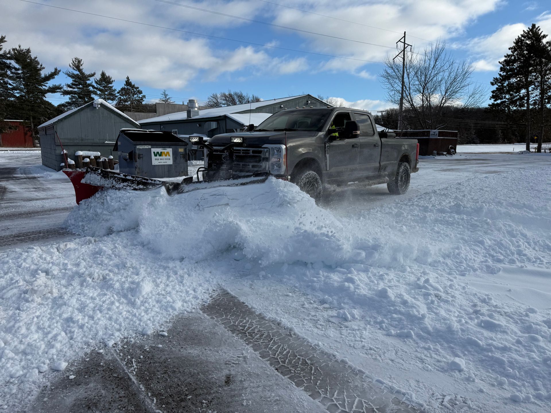 Snowplow truck clearing snow from a driveway during recurring driveway clearing for winter.