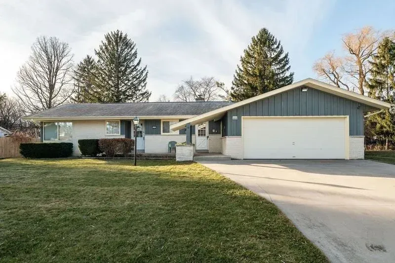 Single-story house with attached two-car garage, front lawn, and driveway in a suburban neighborhood