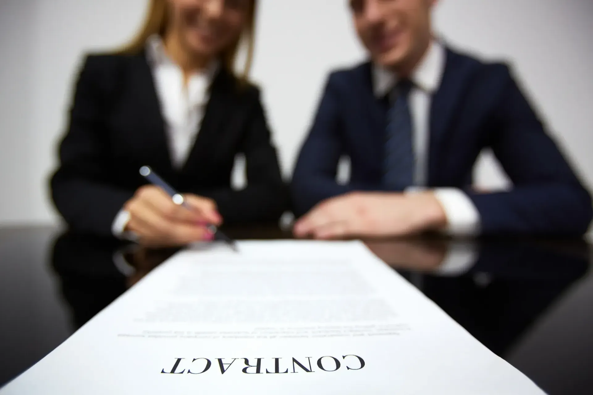 Businesspeople signing a contract, focus on document labeled