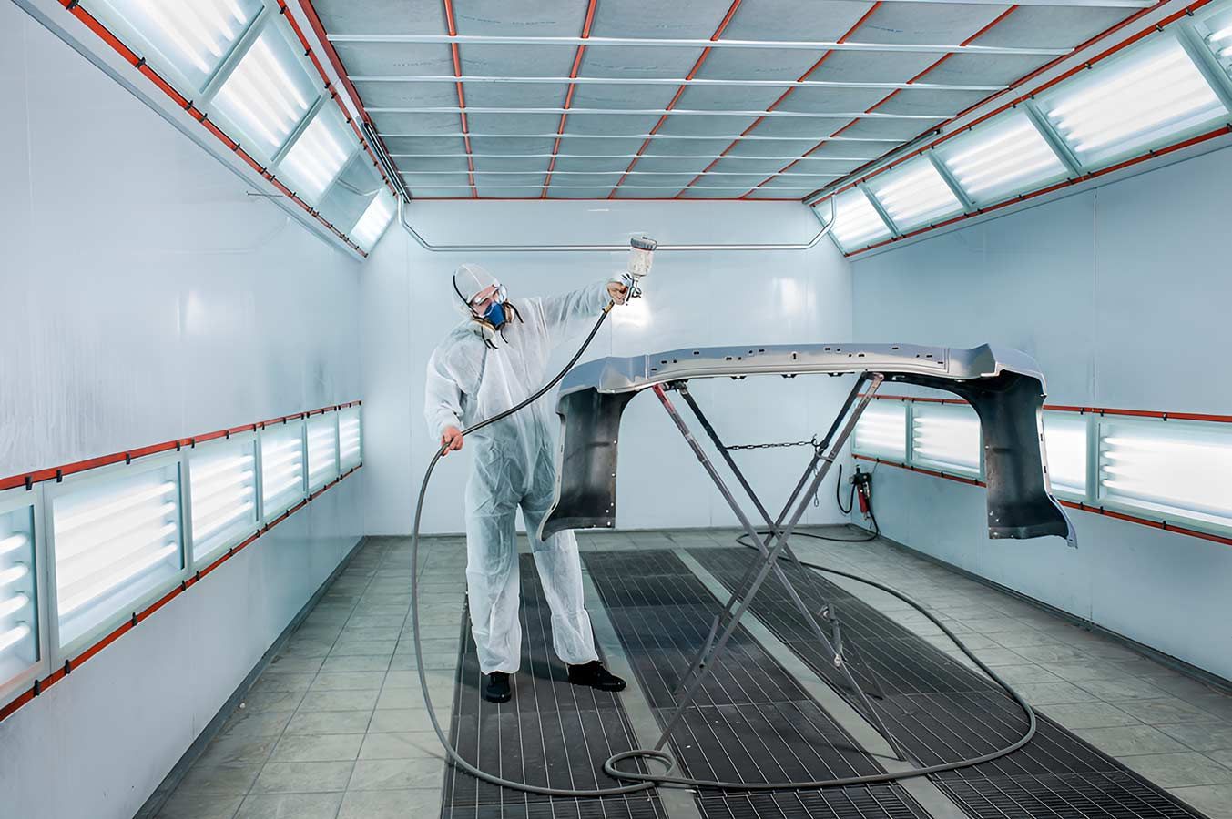 A Man Is Painting A Car In A Paint Booth — Milini's Panel, Paint & Towing in Tully, QLD