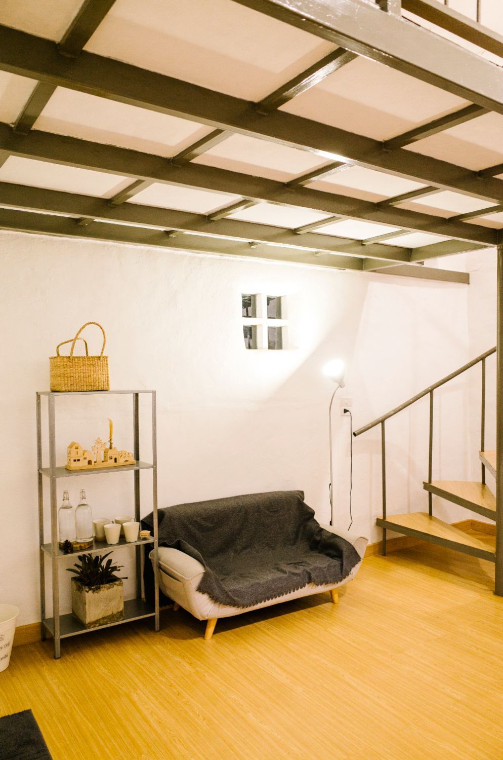 A living room with a couch , shelves , and stairs.
