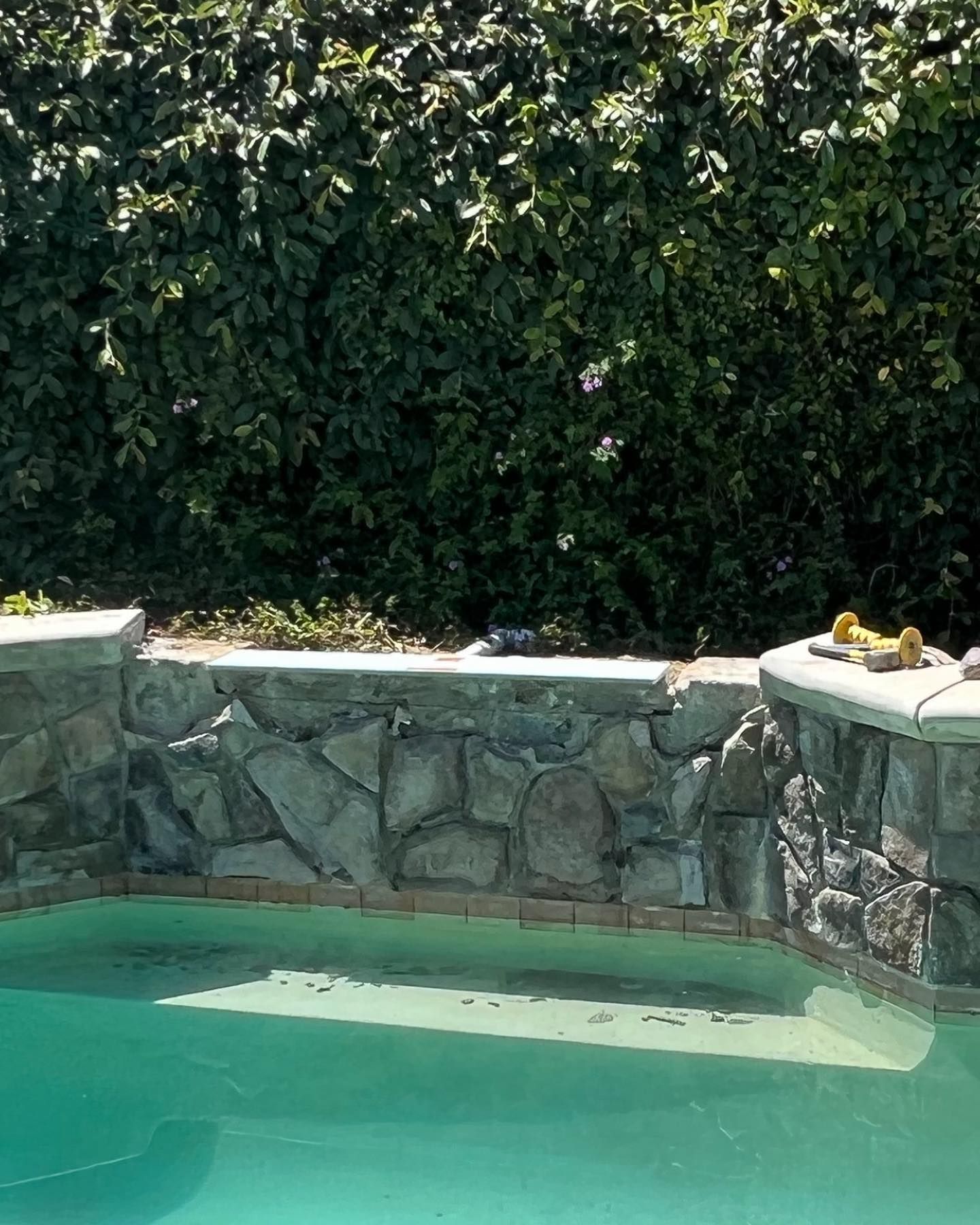 a swimming pool with a stone wall surrounding it
