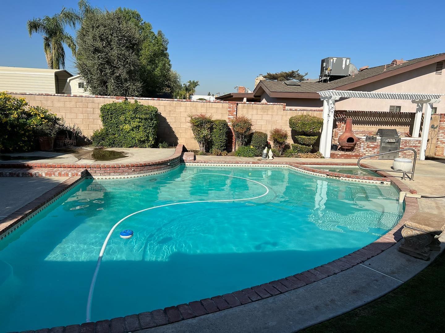 a large swimming pool in a backyard with a house in the background