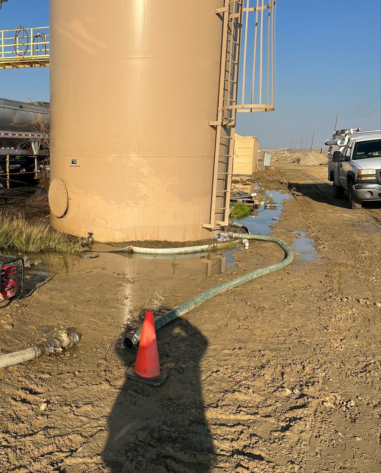 a truck is parked in front of a large tank with a hose attached to it
