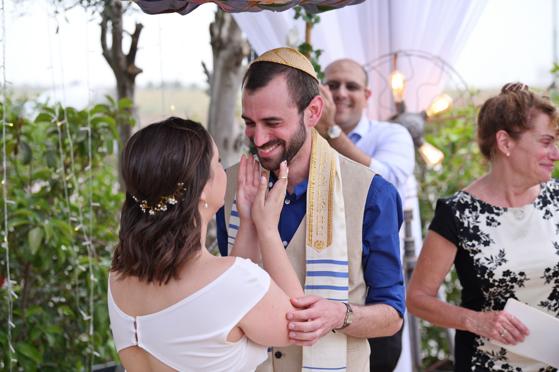 זוג מתחבק במהלך חגיגה בחוץ, כשהאורחים מתערבבים ברקע.