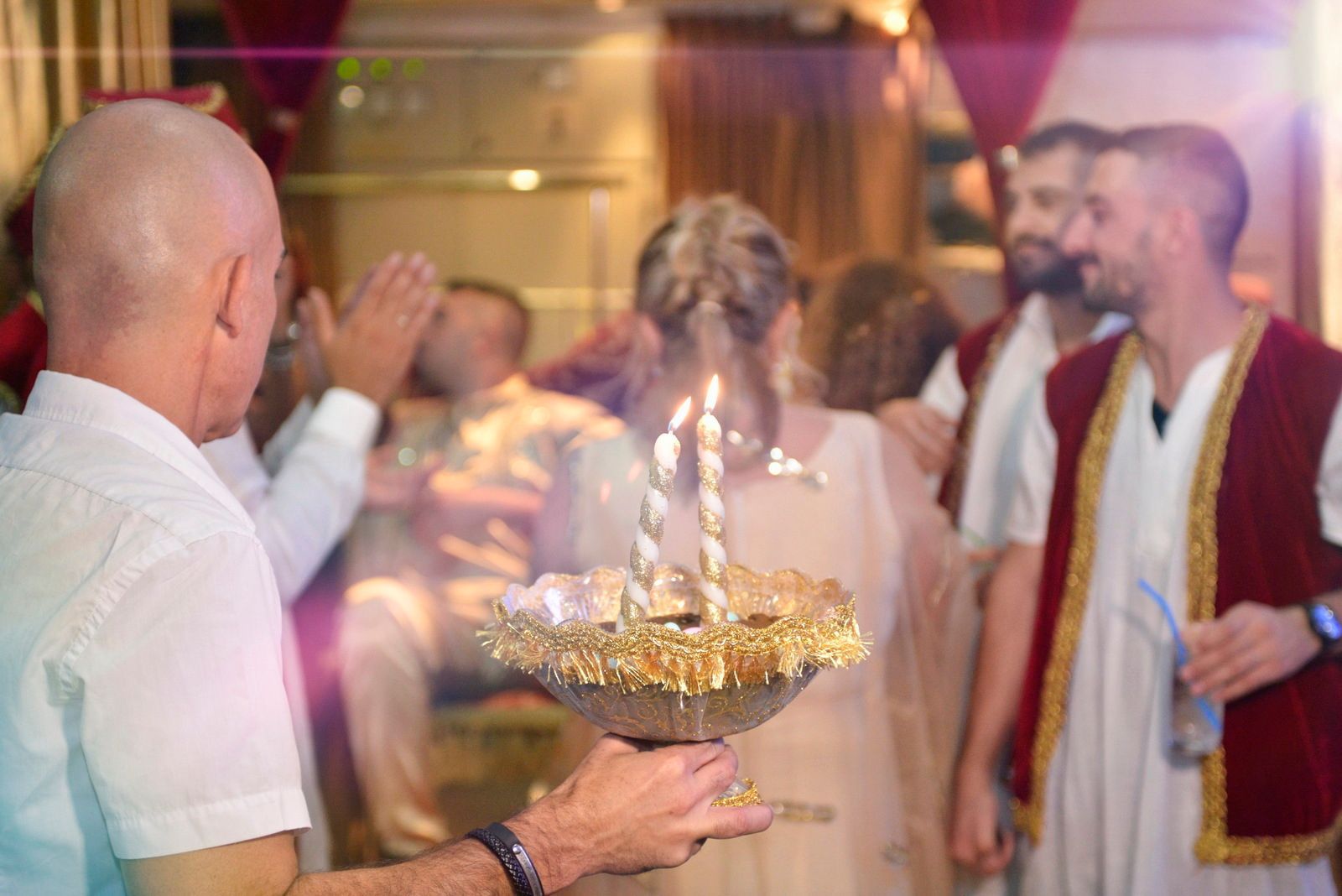 אנשים התאספו סביב מנורת טקס דולקת במהלך חגיגה חגיגית בתוך מבנה. - צילום חינה - גיל דור