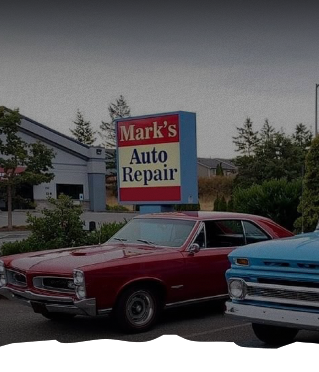 Two cars are parked in front of a sign for mark 's auto repair | Mark's Auto Repair