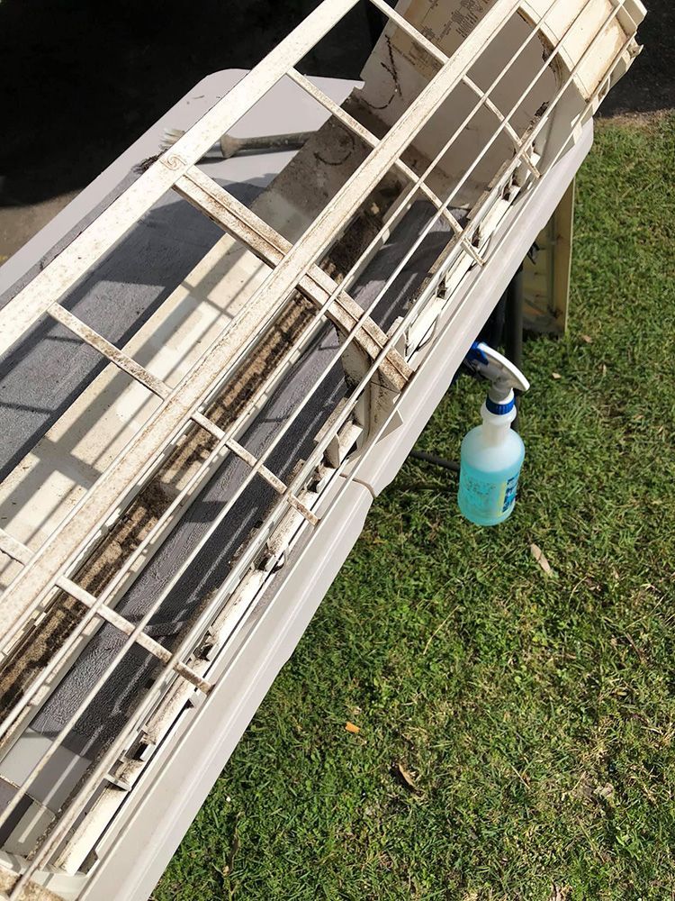 A Dirty Air Conditioner Is Sitting On The Grass Next To A Spray Bottle — More Clean Air In Lake Macquarie, NSW