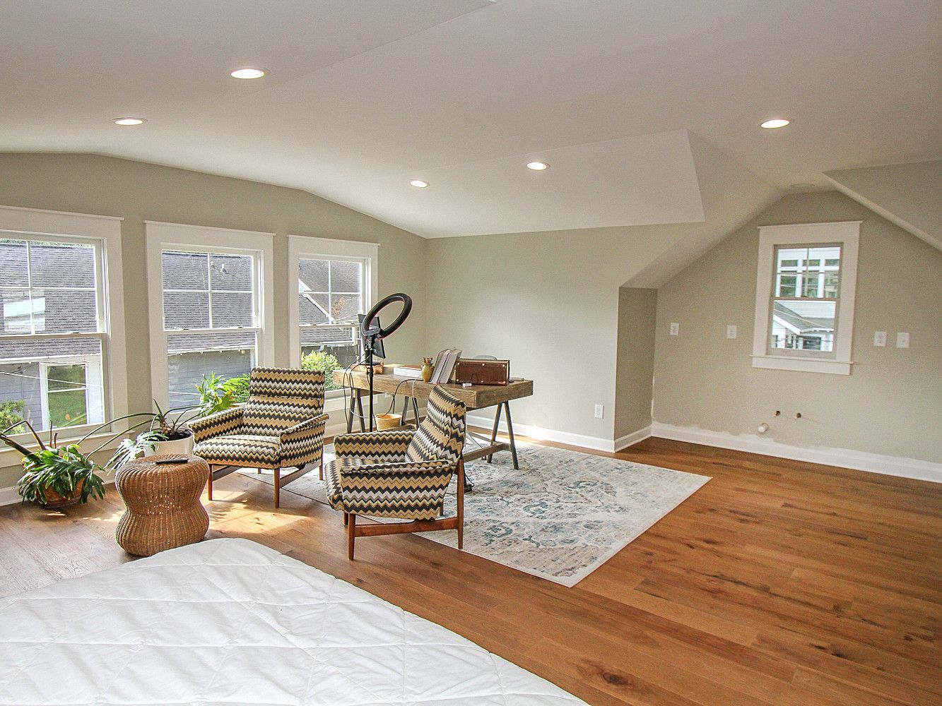 Bright room with hardwood floors, sage walls, and white trim. Two patterned chairs face a desk.