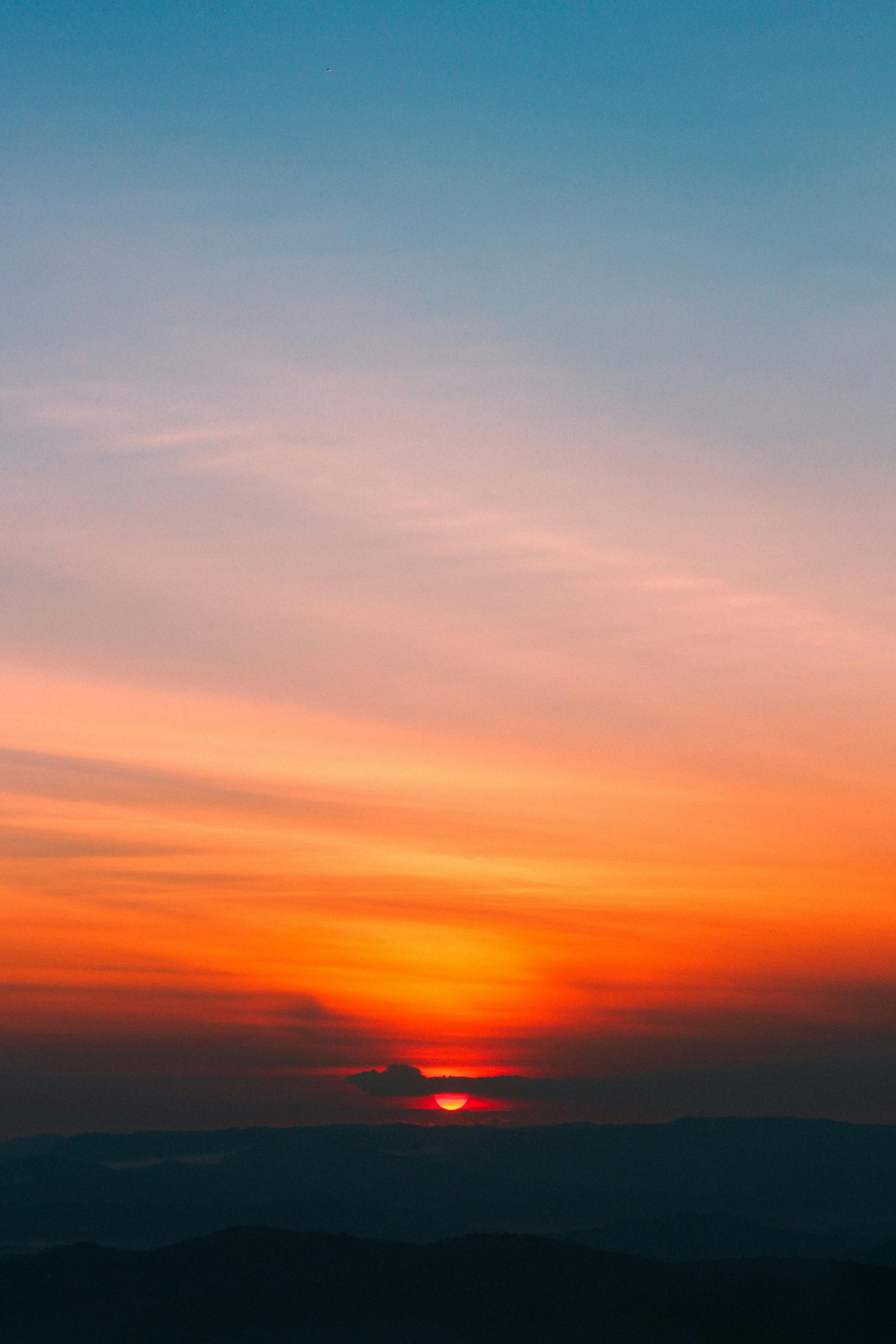 Sunset over mountain silhouettes with vibrant orange and pink hues in the sky.