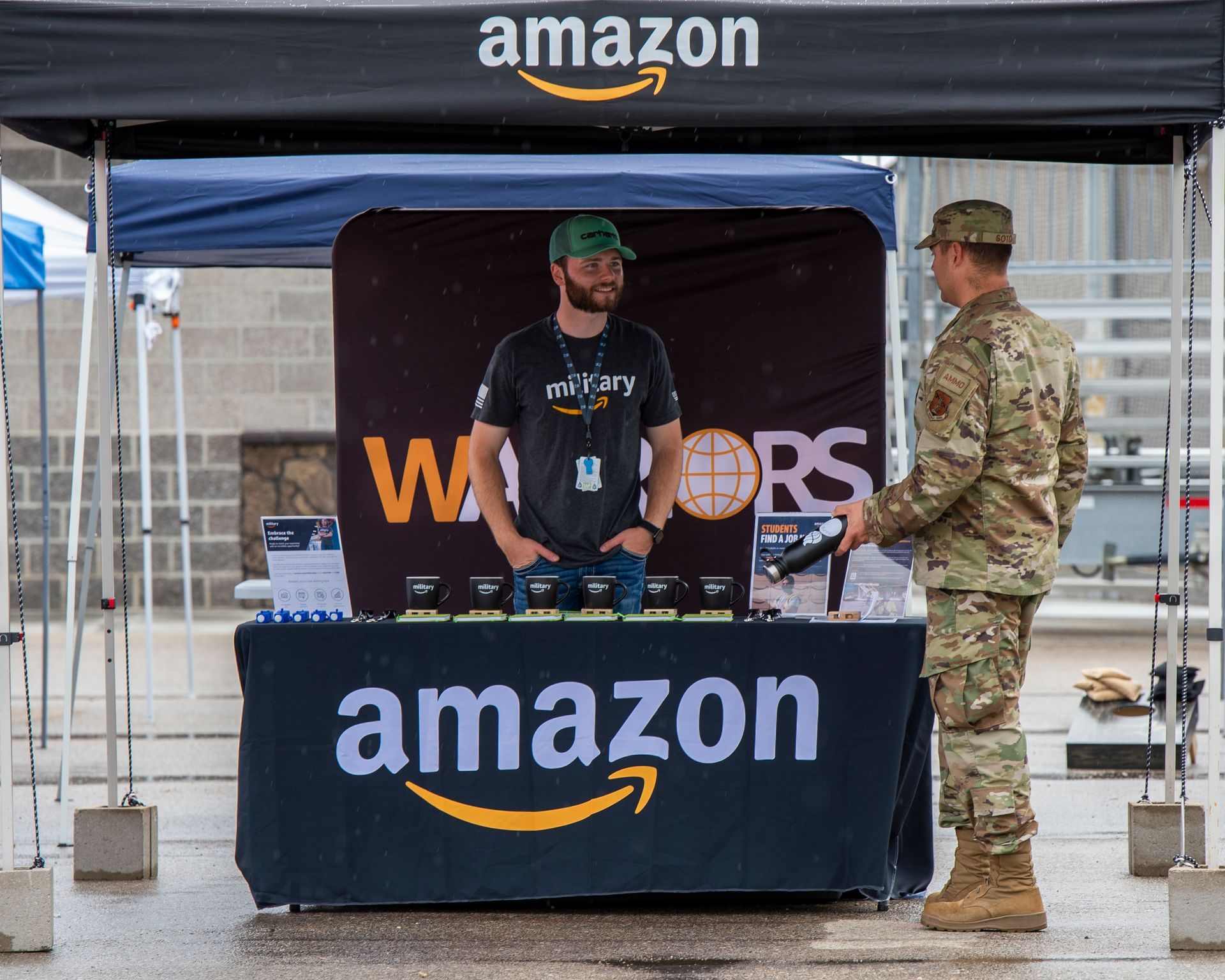 A man in a military uniform is standing in front of an amazon booth.