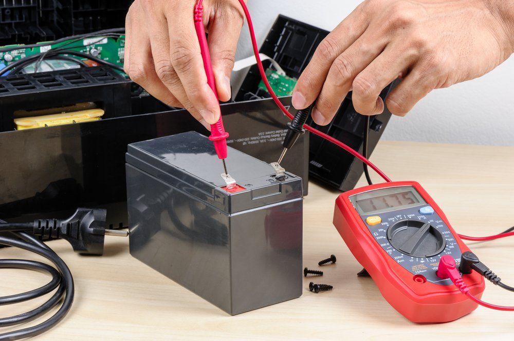 Technician Measuring The Voltage Of Battery — Barnes Electrical in Gladstone, QLD