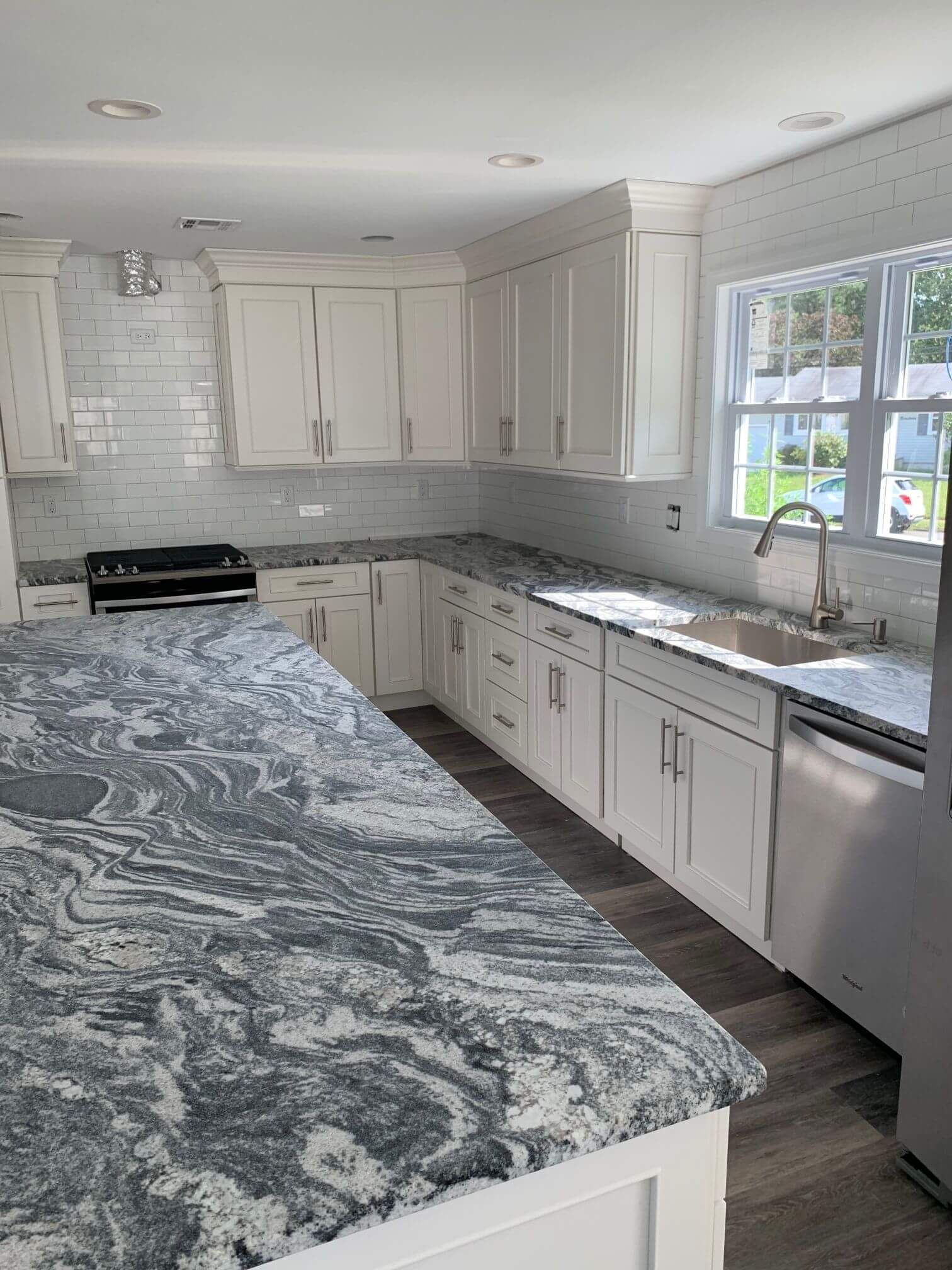 A kitchen with white cabinets and granite counter tops.