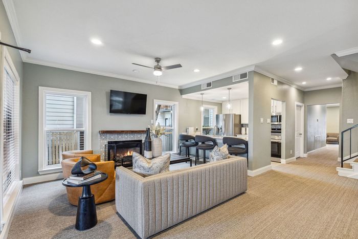 Living room with fireplace, sofa, and open kitchen; neutral colors, modern style.