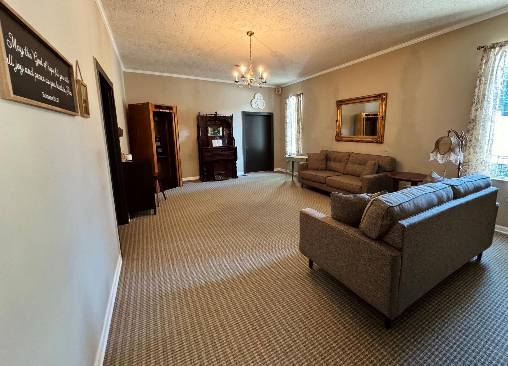 Spacious living room with gray sectional sofa, carpeted floor, wood furniture, and wall mirror.
