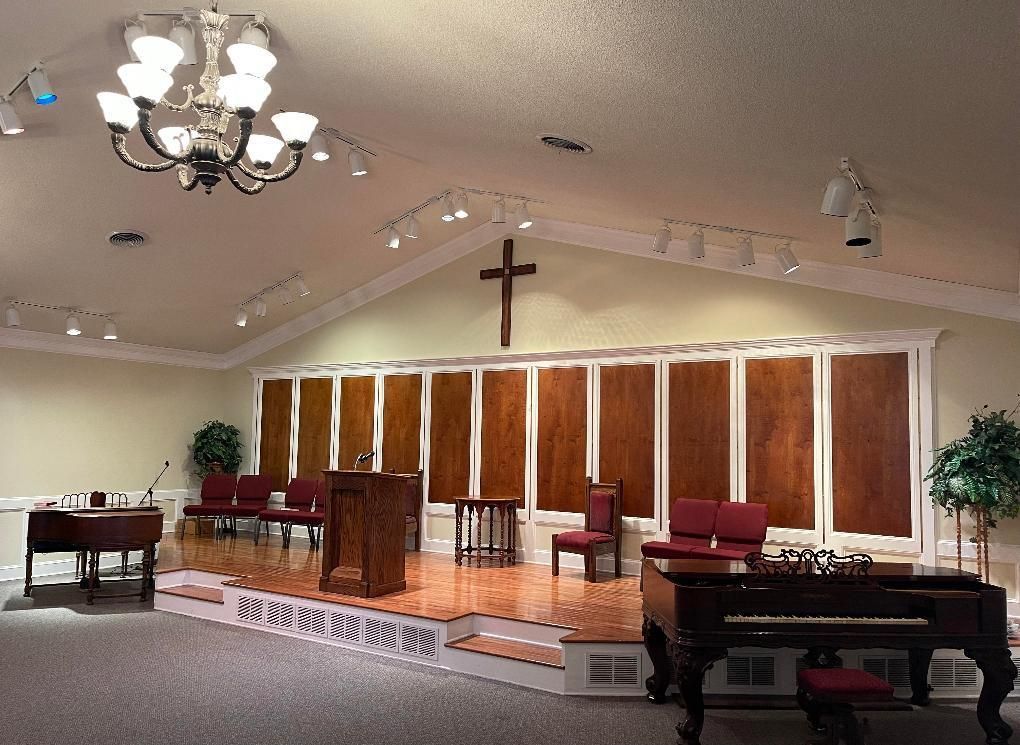 Church sanctuary with cross, choir risers, chandeliers, and a piano on the right