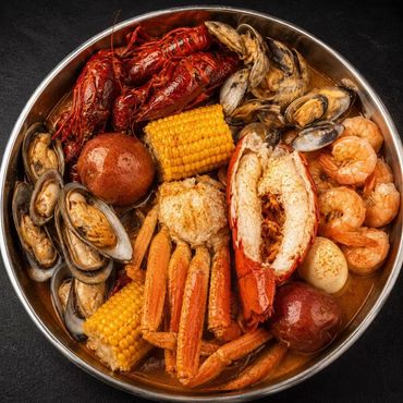 Seafood boil in a metal bowl with crawfish, shrimp, crab, mussels, corn, and potatoes