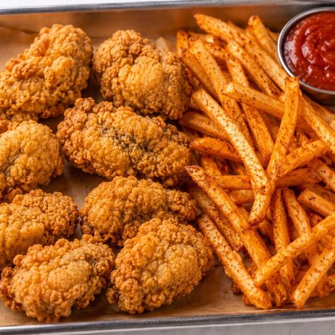 Fried chicken tenders with seasoned fries and a side of ketchup on a tray