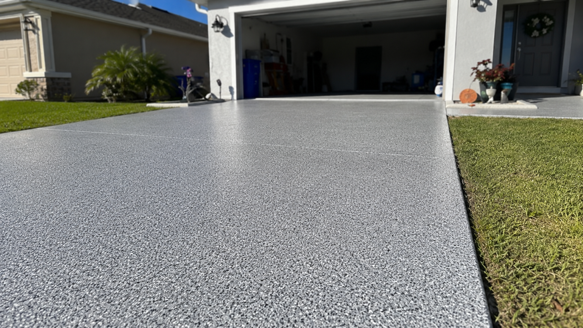 Fresh speckled gray concrete driveway leading to an open garage of a suburban house