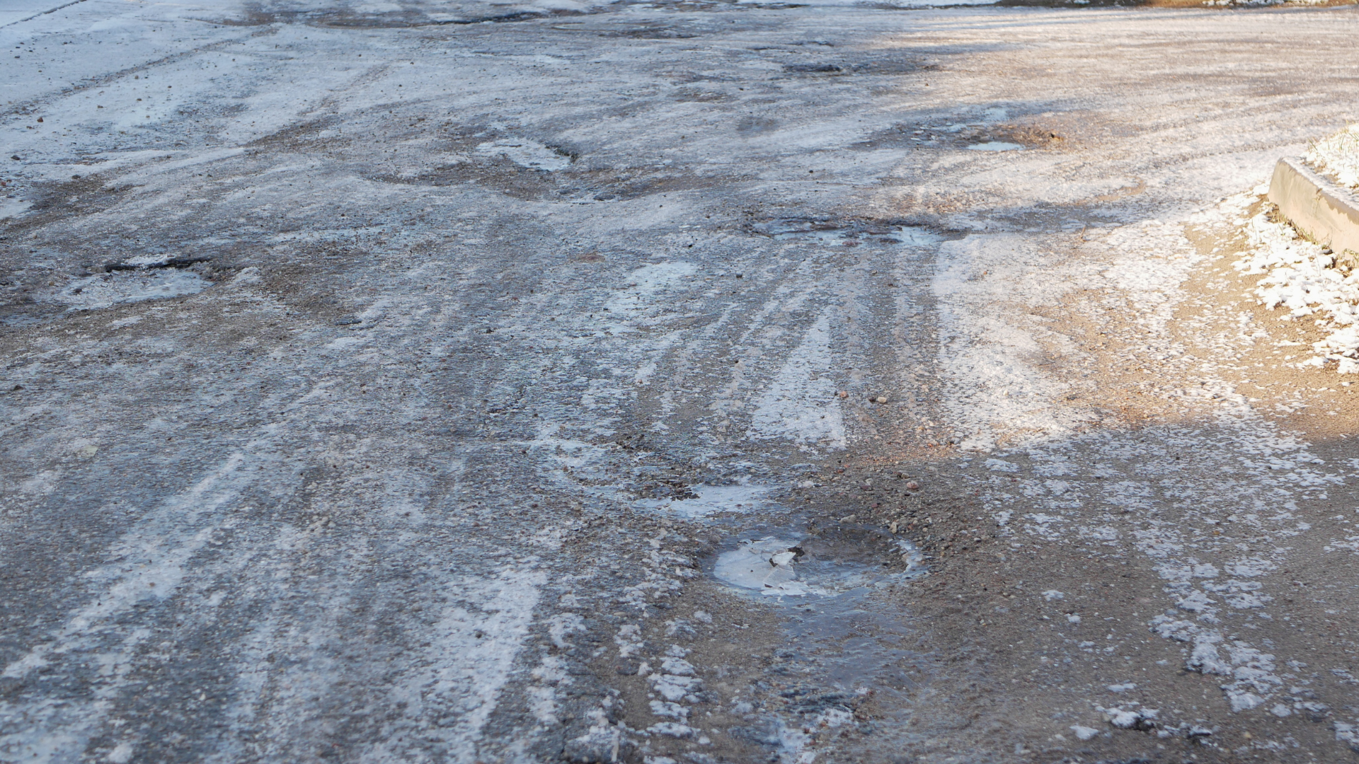 Icy, slushy road surface with patches of snow and tire tracks