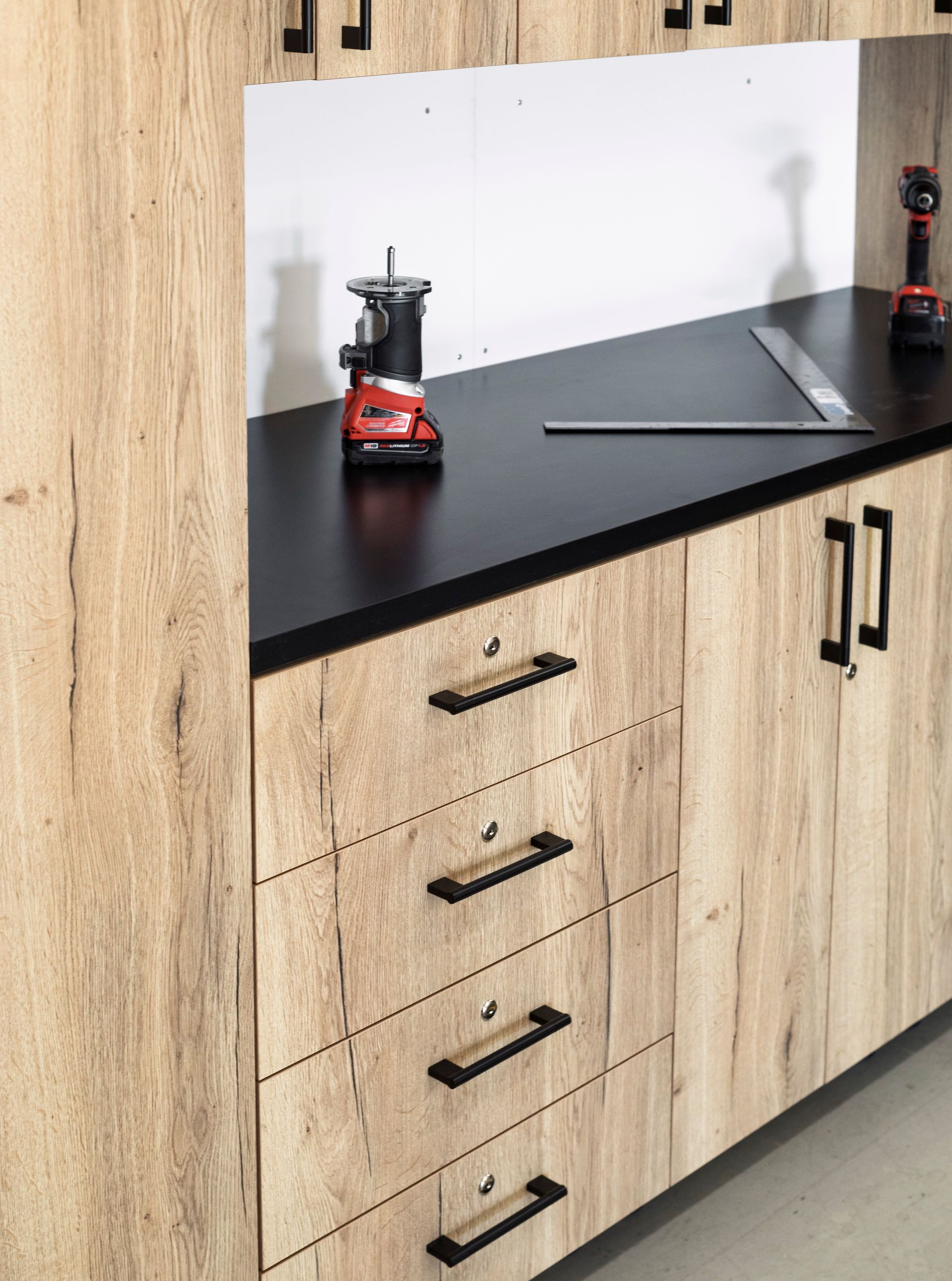 Wood-grain cabinets with black countertop, a red blender, and drawers in a modern kitchen display.