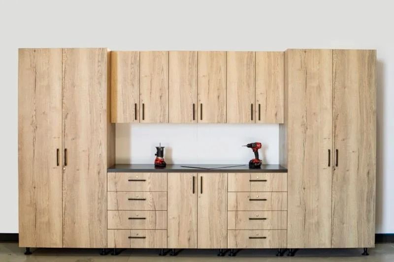 Wood-finish kitchen cabinets with countertop, drawers, and two red drills in the center niche