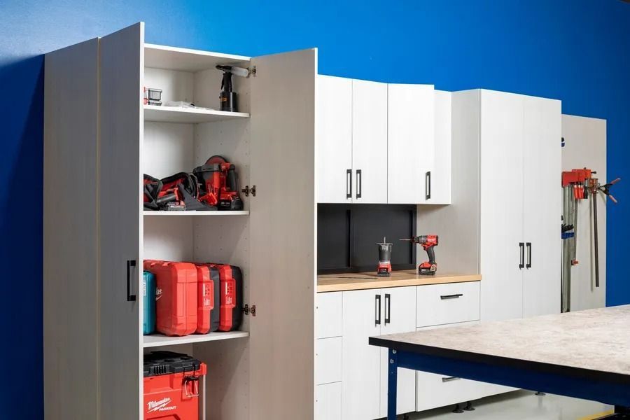 White garage cabinets and shelves with red tools and containers in a workshop area