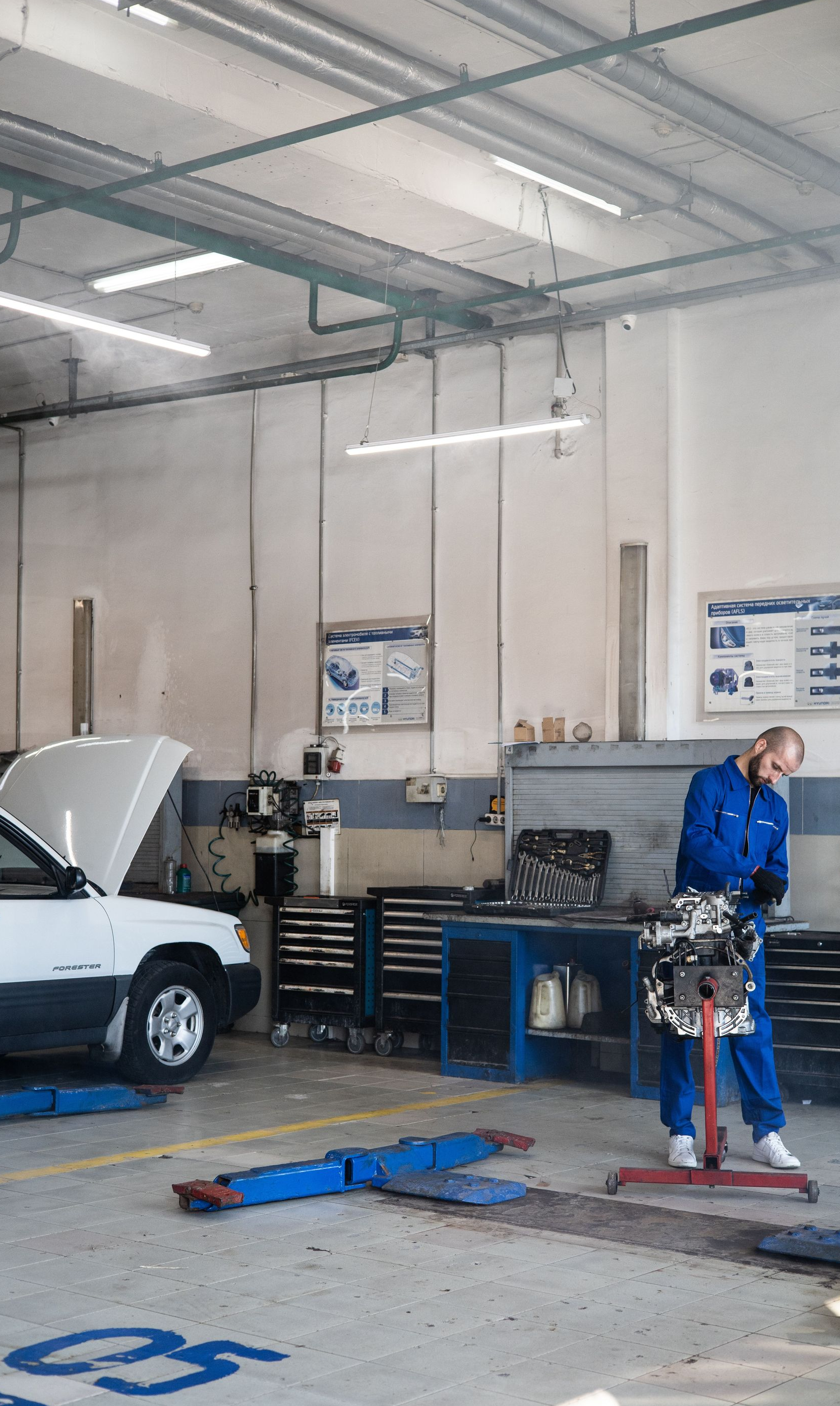 Auto repair shop with a car on a lift and a mechanic standing near tools.