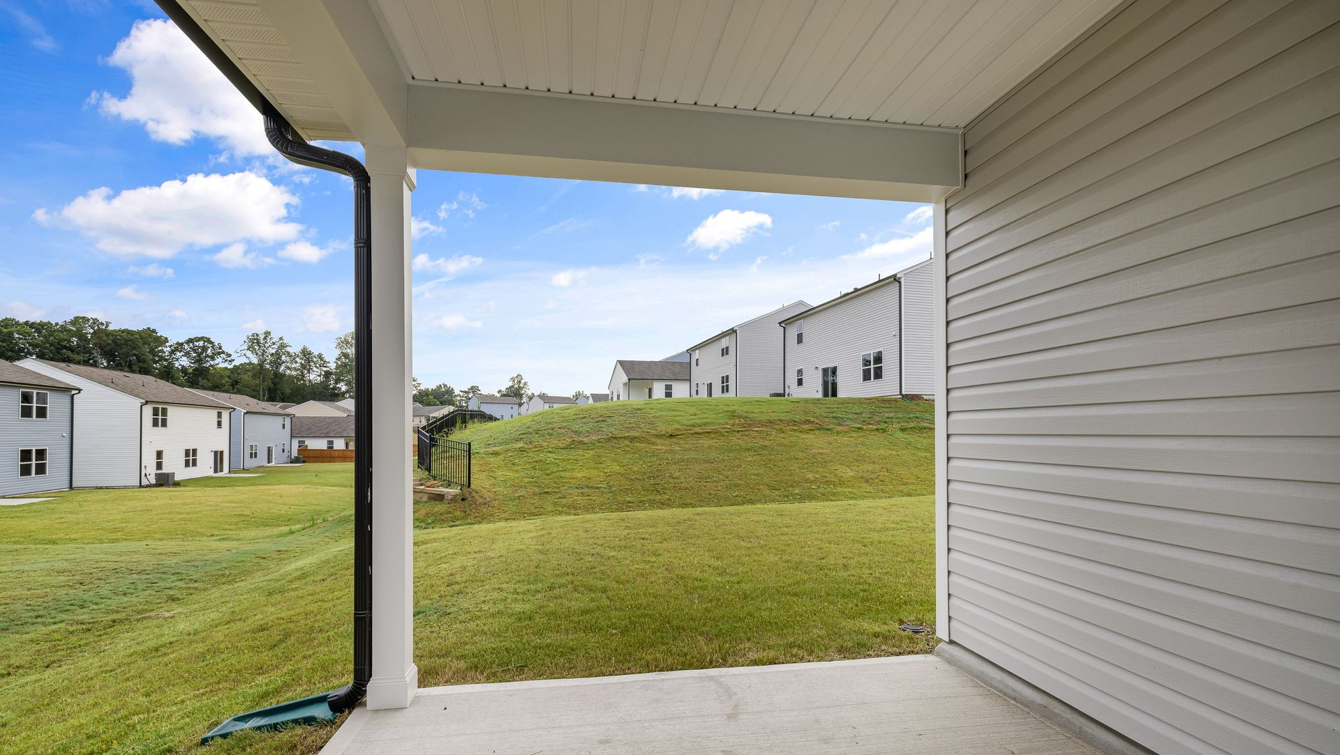 Covered concrete patio overlooking grassy apartment courtyard and neighboring buildings