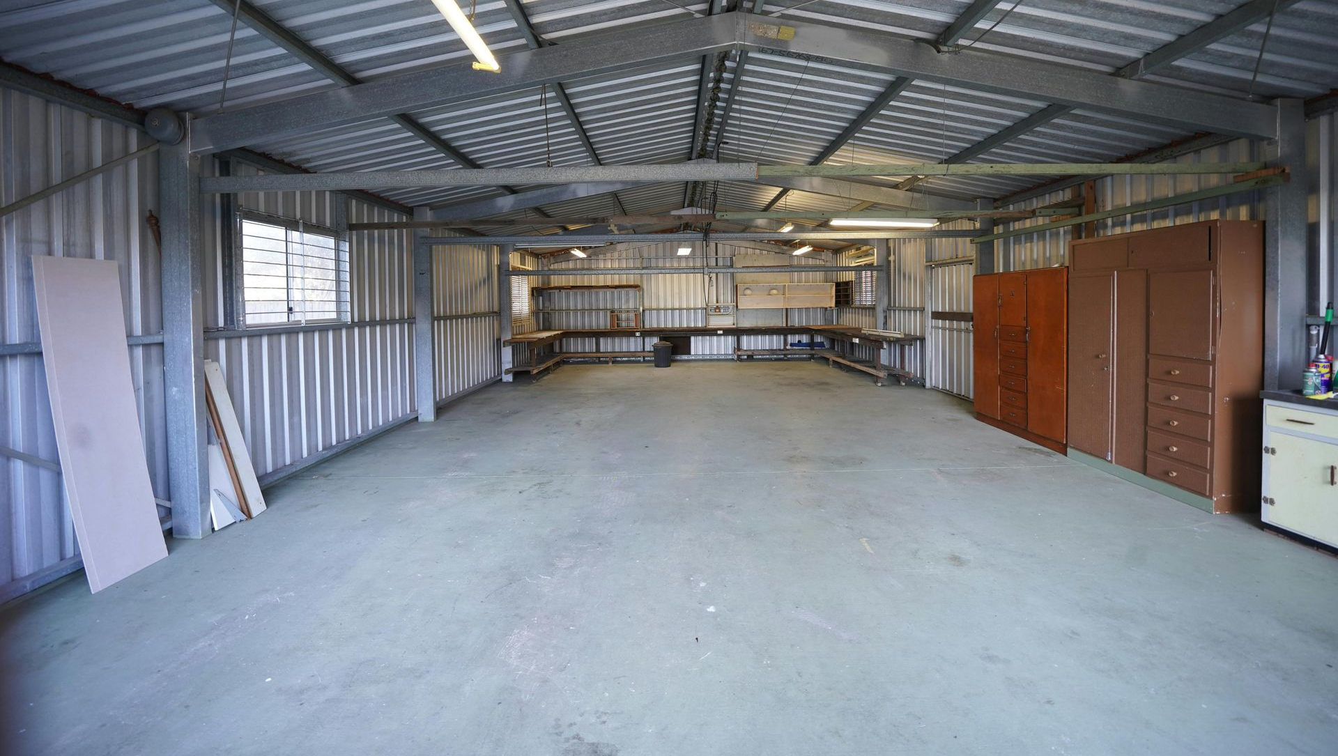 Empty metal warehouse with a concrete floor and storage cabinets along the right wall