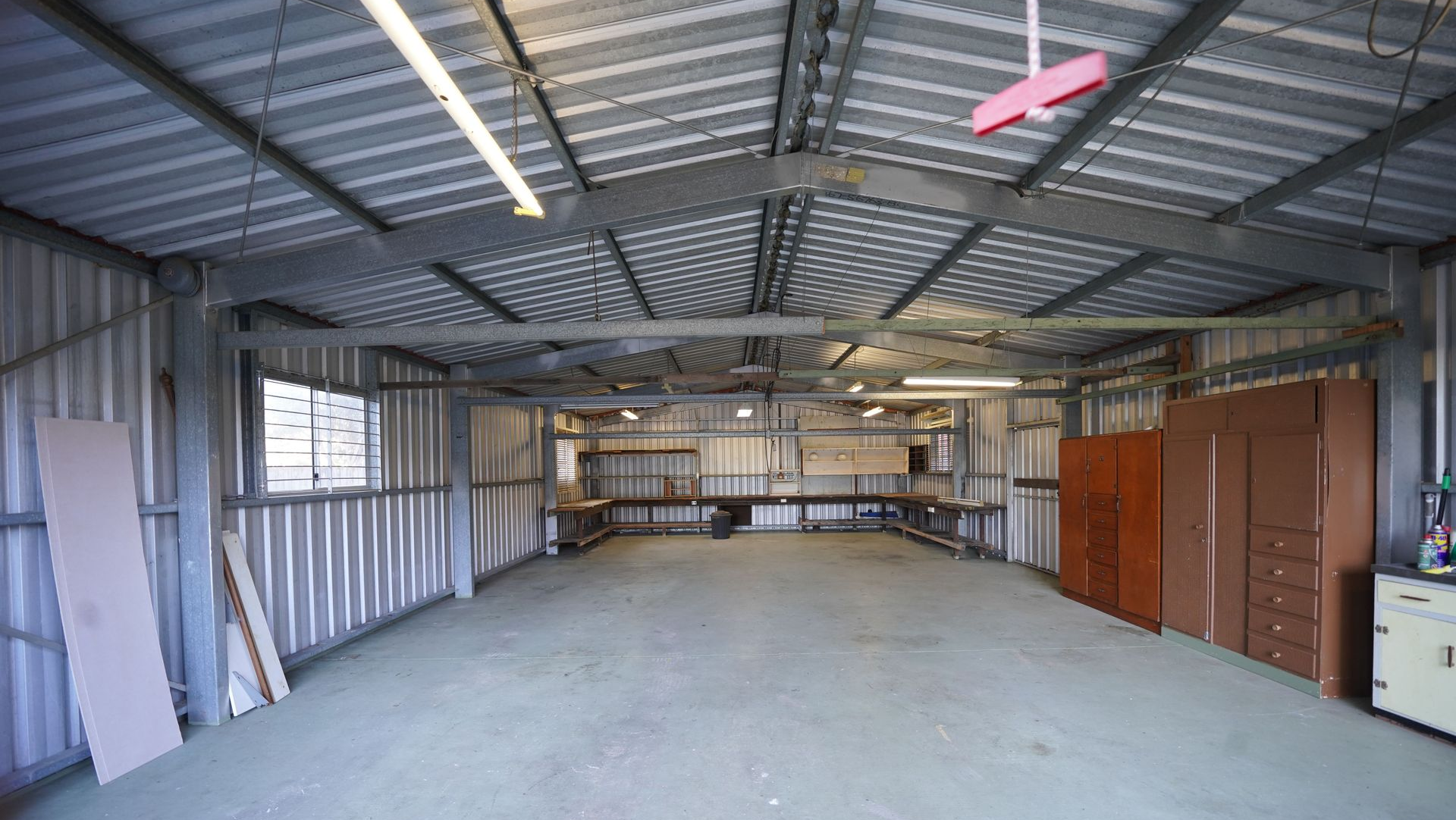 Empty metal warehouse interior with concrete floor, exposed beams, and storage cabinets along the right wall