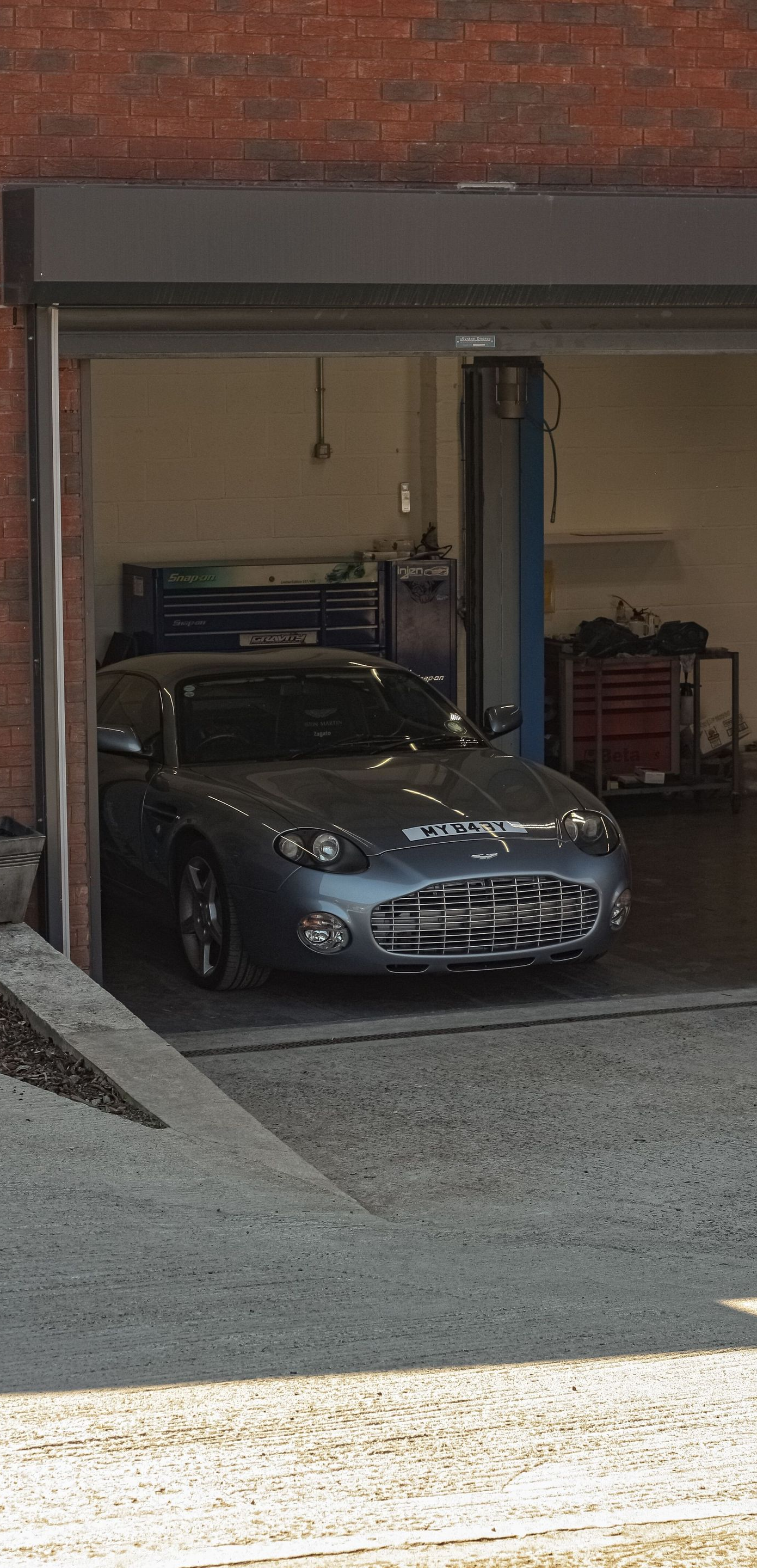 Gray sports car parked in a dim garage with the door open