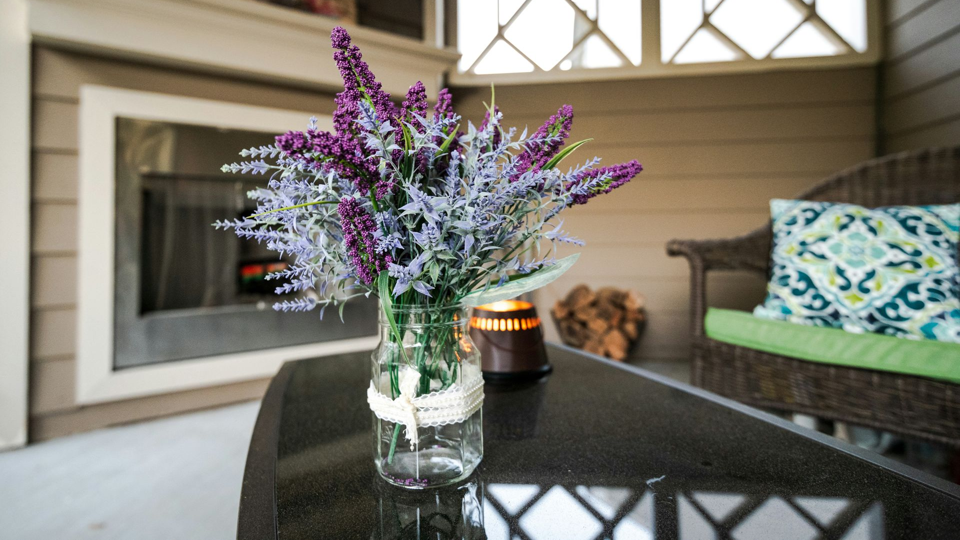 Purple and white flowers in a glass vase on a glossy coffee table in a cozy living room