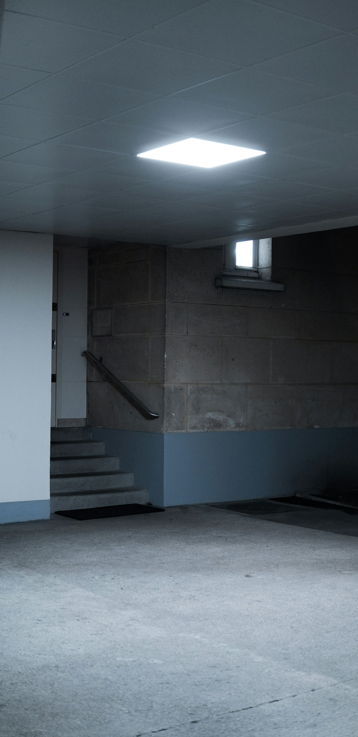 Dim empty interior room with stairs, a doorway, and a bright ceiling light, viewed from a low angle