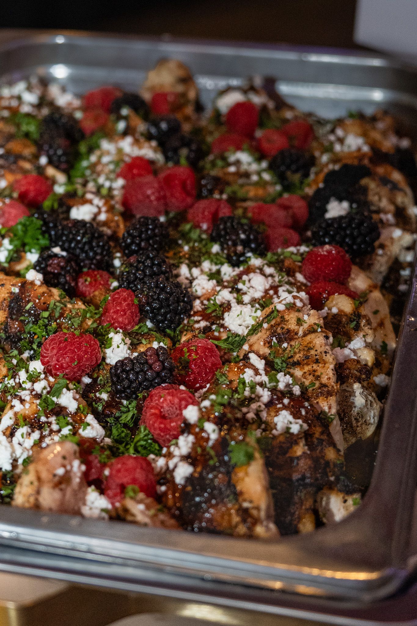 Tray of chocolate dessert topped with whipped cream, raspberries, and chocolate drizzle