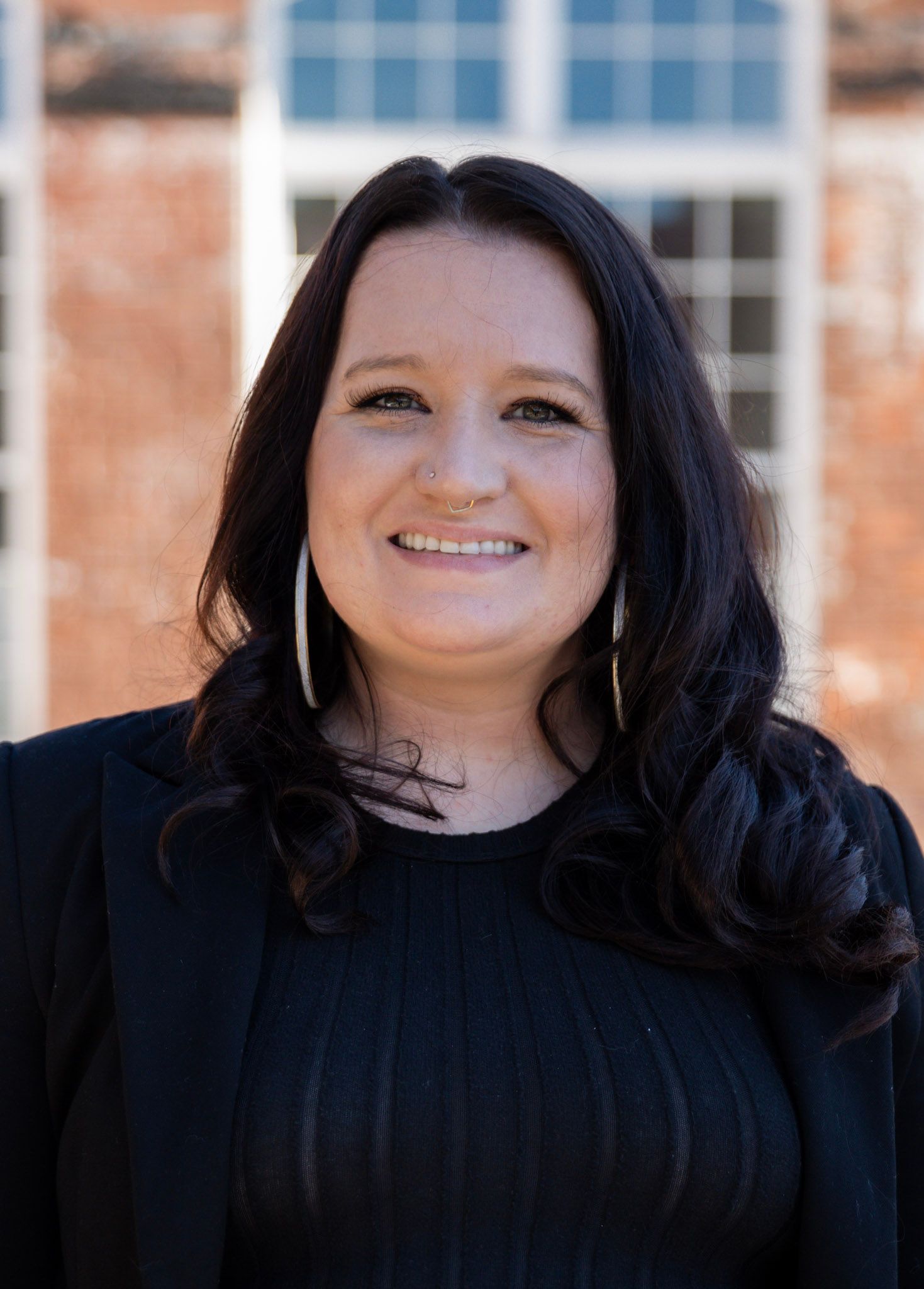 Felicia Keeling smiling in a black sweater standing outdoors in front of a brick building