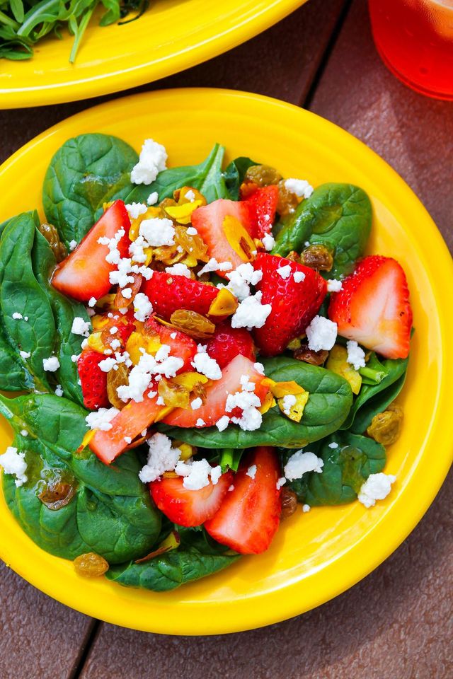 Spinach salad with strawberries and feta on a bright yellow plate