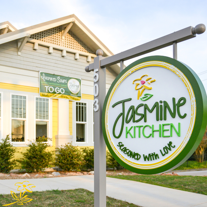 Jasmin Kitchen sign outside a light-colored building with a green-and-white to-go banner