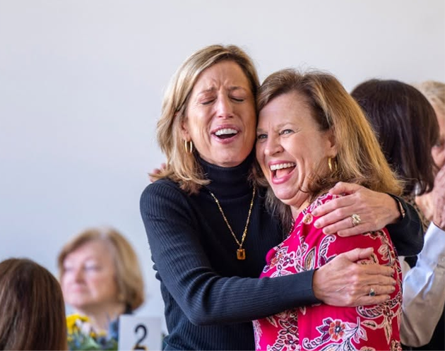 Two women hugging and smiling in a bright indoor setting