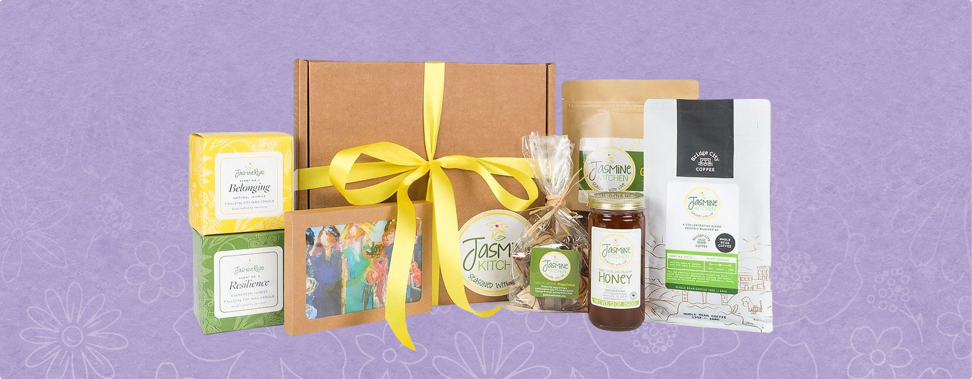 Gift basket with assorted packaged snacks and drinks tied with a yellow ribbon on a purple background