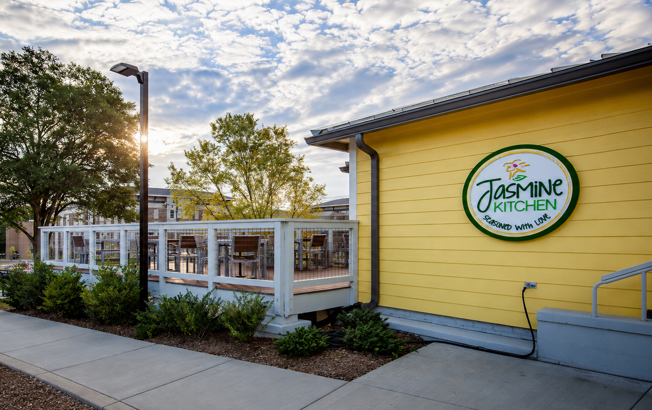 Yellow restaurant exterior with patio seating and a round sign reading “Jasmine Kitchen”