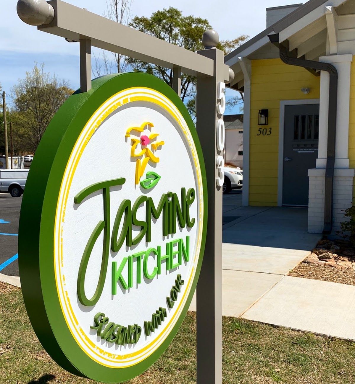 Jasmine Kitchen storefront sign with green circular logo outside a yellow building