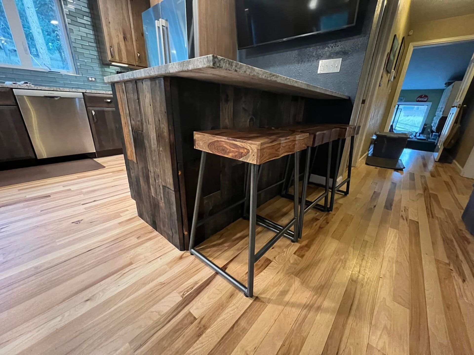 Rustic kitchen island with stools on a hardwood floor.