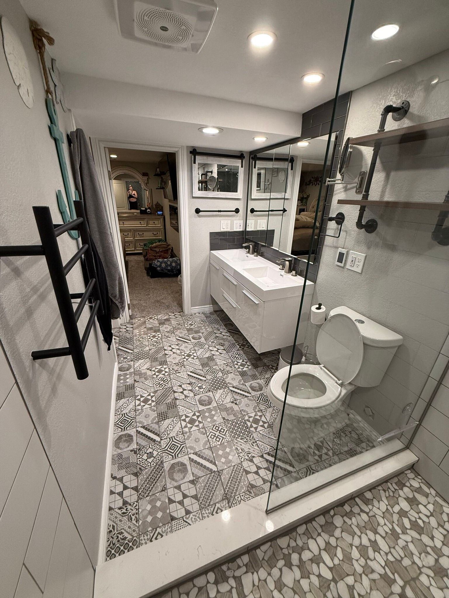 Bathroom with a white vanity, toilet, and glass shower door, patterned floor tiles.
