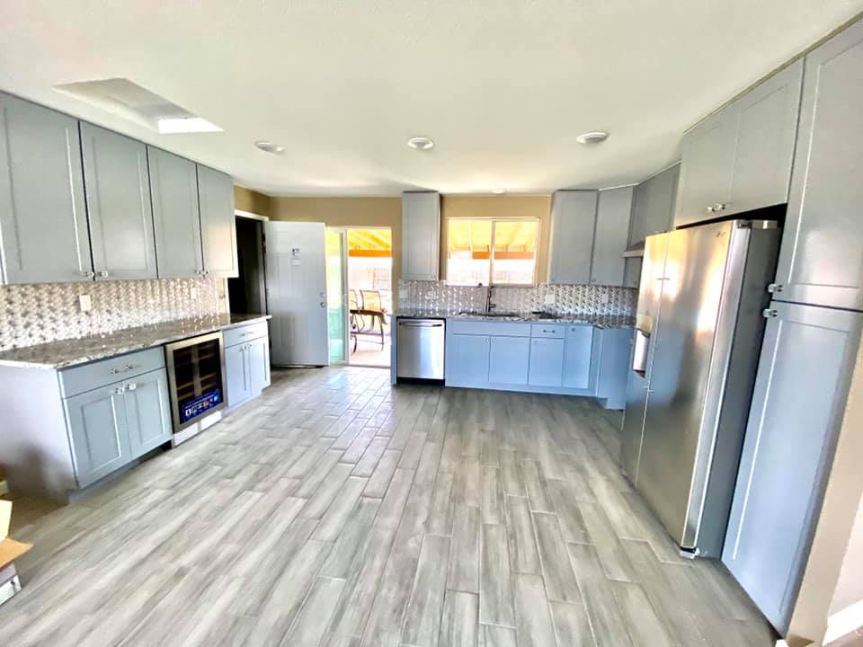 Spacious kitchen with gray cabinets, stainless steel appliances, and wood-look flooring.