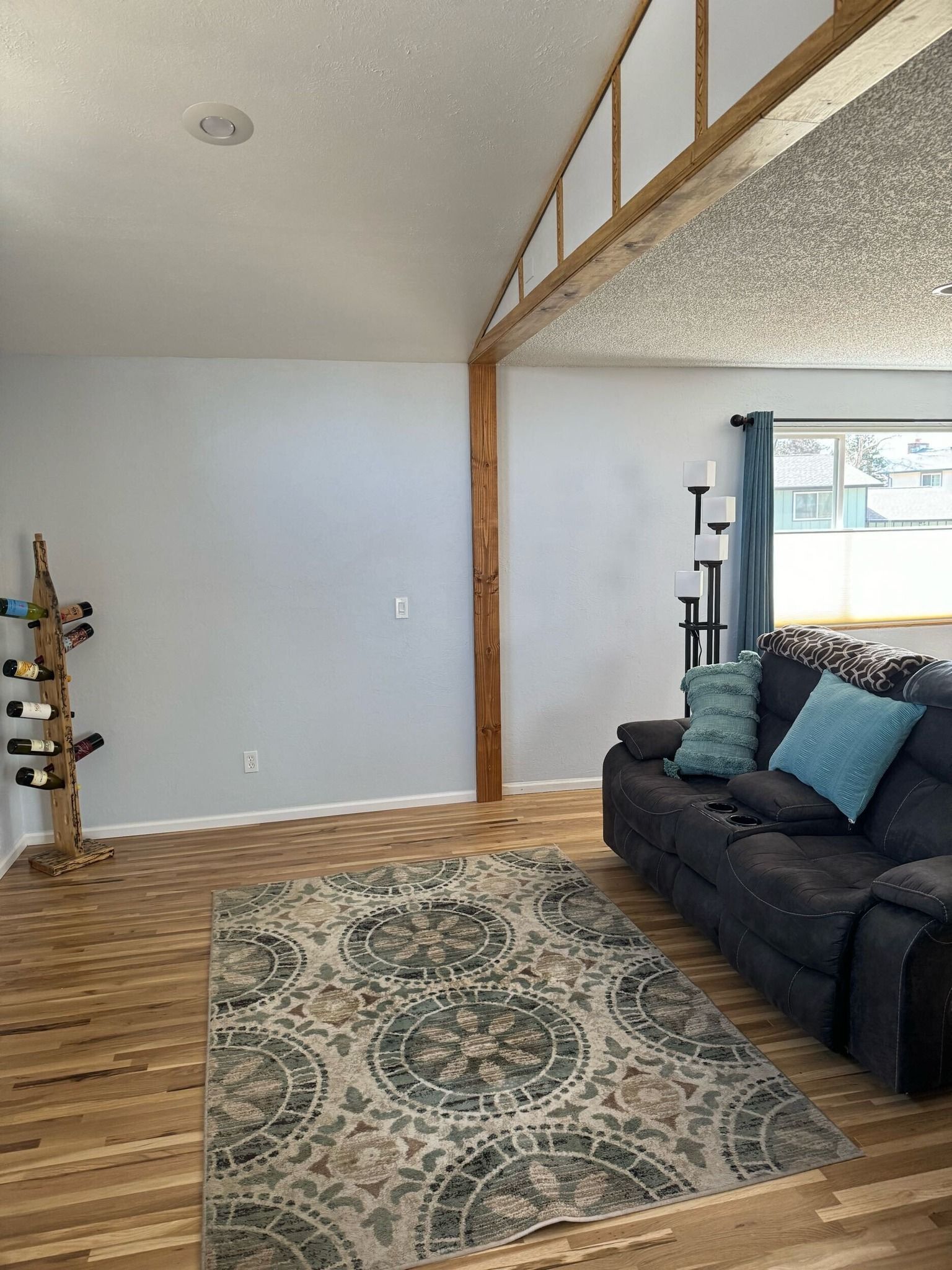 Living room with a wooden floor, a rug, a sofa, and a wine rack.