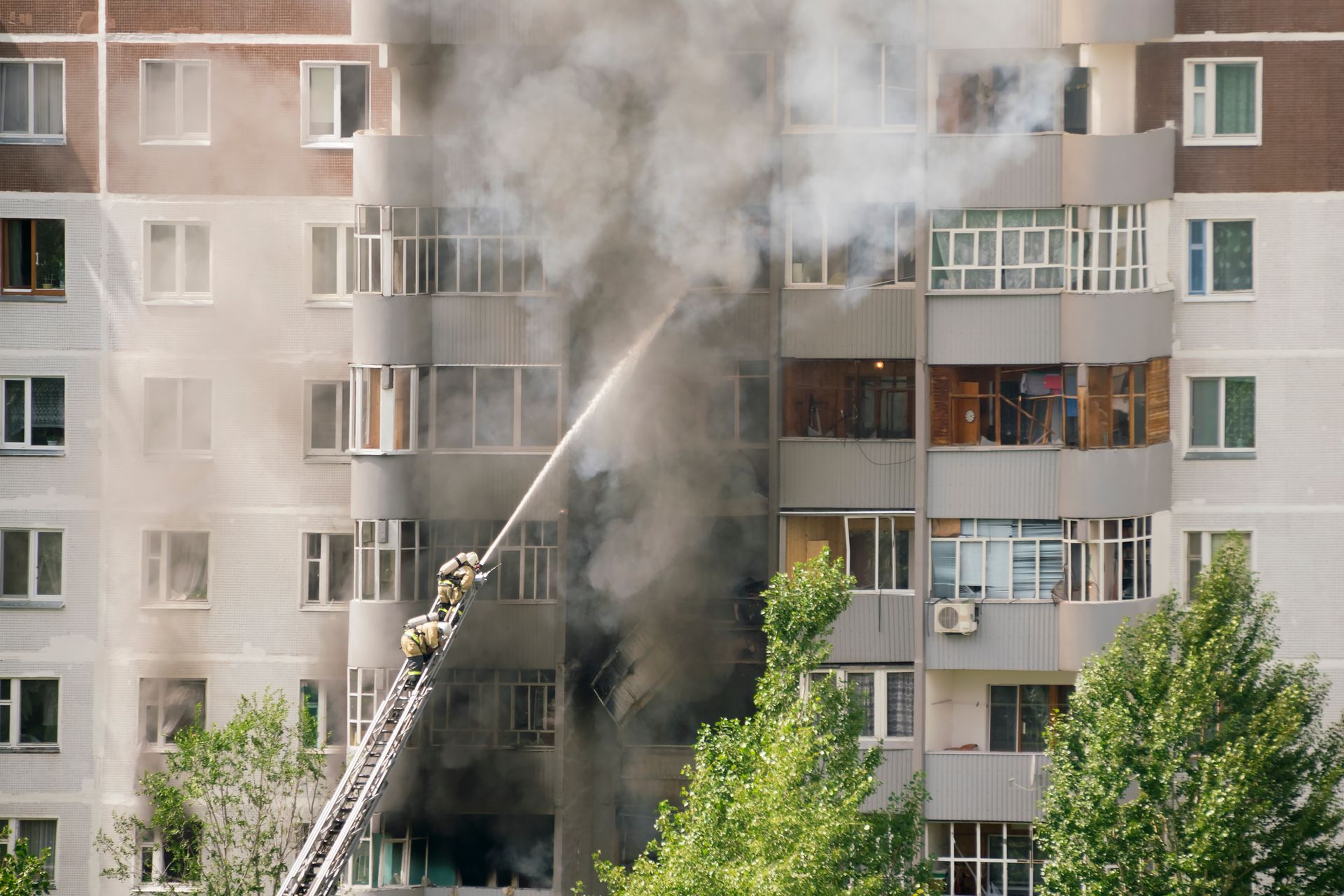 Firefighters battling a blaze at a multi-story apartment building, with smoke billowing from the windows.