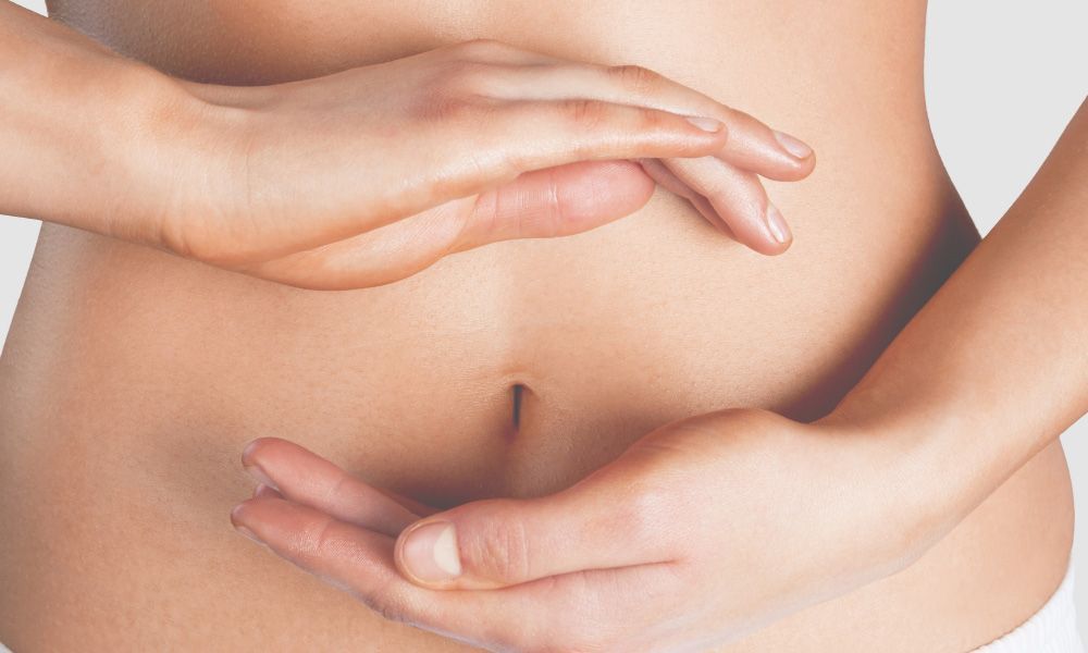 Woman Is Holding Her Stomach With Her Hands — Paradiso Skin & Beauty Studio in Byron Bay, NSW