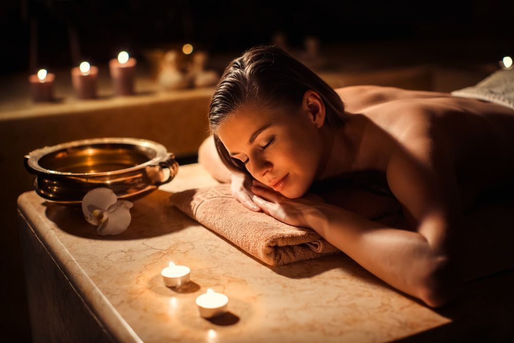 Woman Is Laying On A Table With Candles In A Spa — Paradiso Skin & Beauty Studio in Byron Bay, NSW